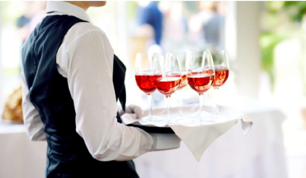 Waiter holding five glasses of rose wine
