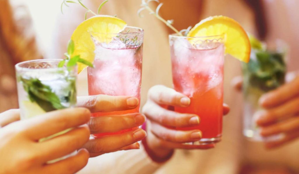 Four people holding red and green cocktails